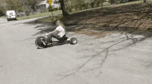 a woman is riding a tricycle down a road with a yellow sign that says " do not enter "