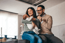 a man and woman are sitting on a couch with a baby