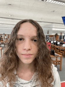 a woman with long curly hair is standing in a library .