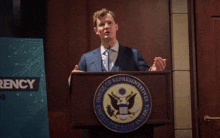 a man stands behind a podium that says house of representatives on it