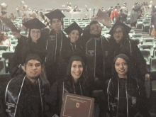 a group of graduates are posing for a photo and one of them is wearing a cap and gown that says university of phoenix