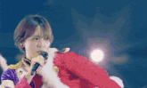a girl singing into a microphone while wearing a santa outfit