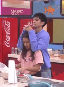 a man is hugging a woman in a kitchen with a coca cola fridge in the background