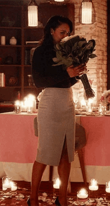 a woman is holding a bouquet of flowers in front of a table .