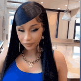 a woman wearing a blue top and a gold chain necklace