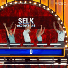 a group of people raising their arms in the air in front of a screen that says selk okotoks ab