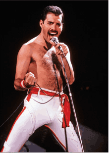 a shirtless man singing into a microphone with his fist raised