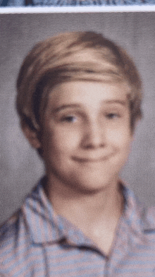 a young boy with blonde hair is smiling for a picture