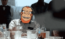 a man wearing a gorilla mask sits at a table with glasses and bottles