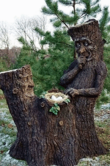 a statue of a tree stump with a face carved into it is sitting next to a bird nest .