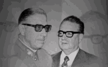 a black and white photo of two men wearing sunglasses