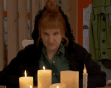 a woman is sitting at a table with candles and making a face .