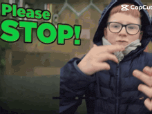 a boy in a hooded jacket points to a sign that says " please stop "