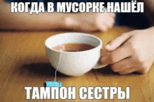 a person is holding a cup of tea on a table .