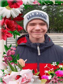 a boy wearing a beanie with the word boss on it smiles in front of flowers