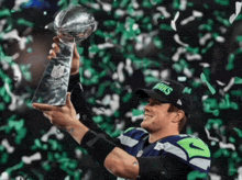 a man in a seahawks hat holds a trophy