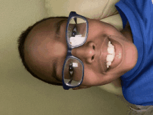 a boy wearing glasses and a blue shirt smiles