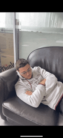 a man in a thinkpad sweatshirt is sleeping in a chair