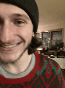 a man wearing a beanie and a sweater is smiling in a living room .