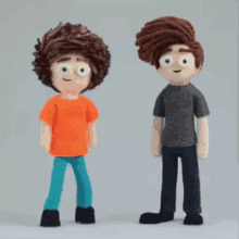 two stuffed boys are standing next to each other and one is wearing an orange shirt