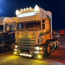 a scania truck is parked in front of a truck that says stirnim