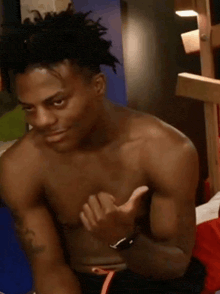 a shirtless man with dreadlocks giving a thumbs up