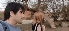 a man and a woman are standing next to a tree and the man is wearing a blue shirt with the word gopro on the sleeve