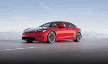 a red tesla model s driving on a road