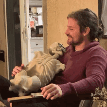 a man is sitting in a chair holding a stuffed animal skeleton .