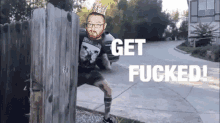 a man with a crown on his head is peeking over a wooden fence with the words get fucked