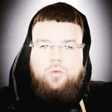 a man with a beard and glasses is wearing a hooded jacket .