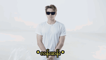a man in a white shirt is standing in front of a white background with a foreign language written on it