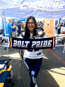 a woman holds up a scarf that says bolt pride