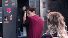 a man in a red shirt is standing next to a girl in a locker with a netflix logo on it