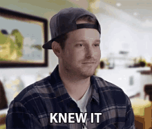 a man wearing a plaid shirt and a baseball cap says " knew it "