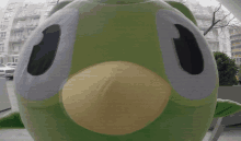 a green frog mascot with a yellow beak and large eyes