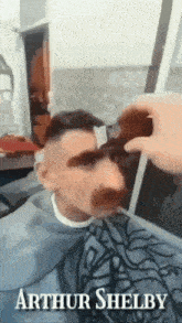 a man getting his hair cut by a barber named arthur shelby