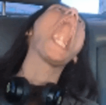 a woman is yawning while sitting in a car .