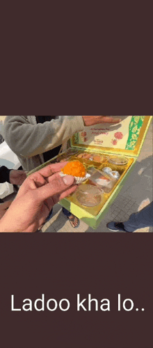 a man with a beard is eating a piece of food with the words ladoo kha lo on the bottom .