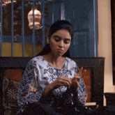 a woman sits on a couch with her hands on her fingers