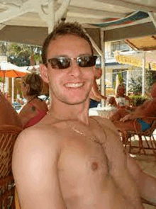 a shirtless man wearing sunglasses is sitting in a chair at the beach .