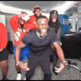 a group of men are dancing together in a room and one of them is wearing a red hoodie .