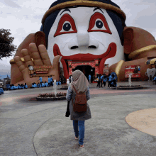 a woman stands in front of a giant statue of a clown and a sign that says " the legend "