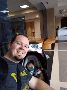 a man is holding a baby in a stroller while wearing a shirt that says peace on it