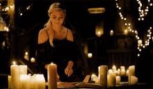 a woman is sitting at a table with candles and a book