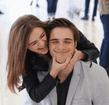 a woman is putting her hand on a man 's face and smiling