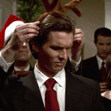 a man in a suit and tie is wearing reindeer antlers