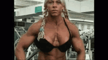 a very muscular woman is standing in a gym with her hands on her hips .