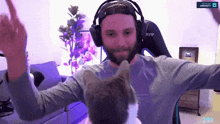 a man with a beard and headphones is playing with a cat in a living room .