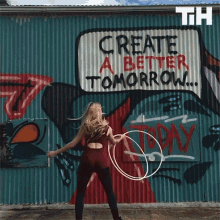 a woman is playing with a hula hoop in front of a graffiti wall that says create a better tomorrow